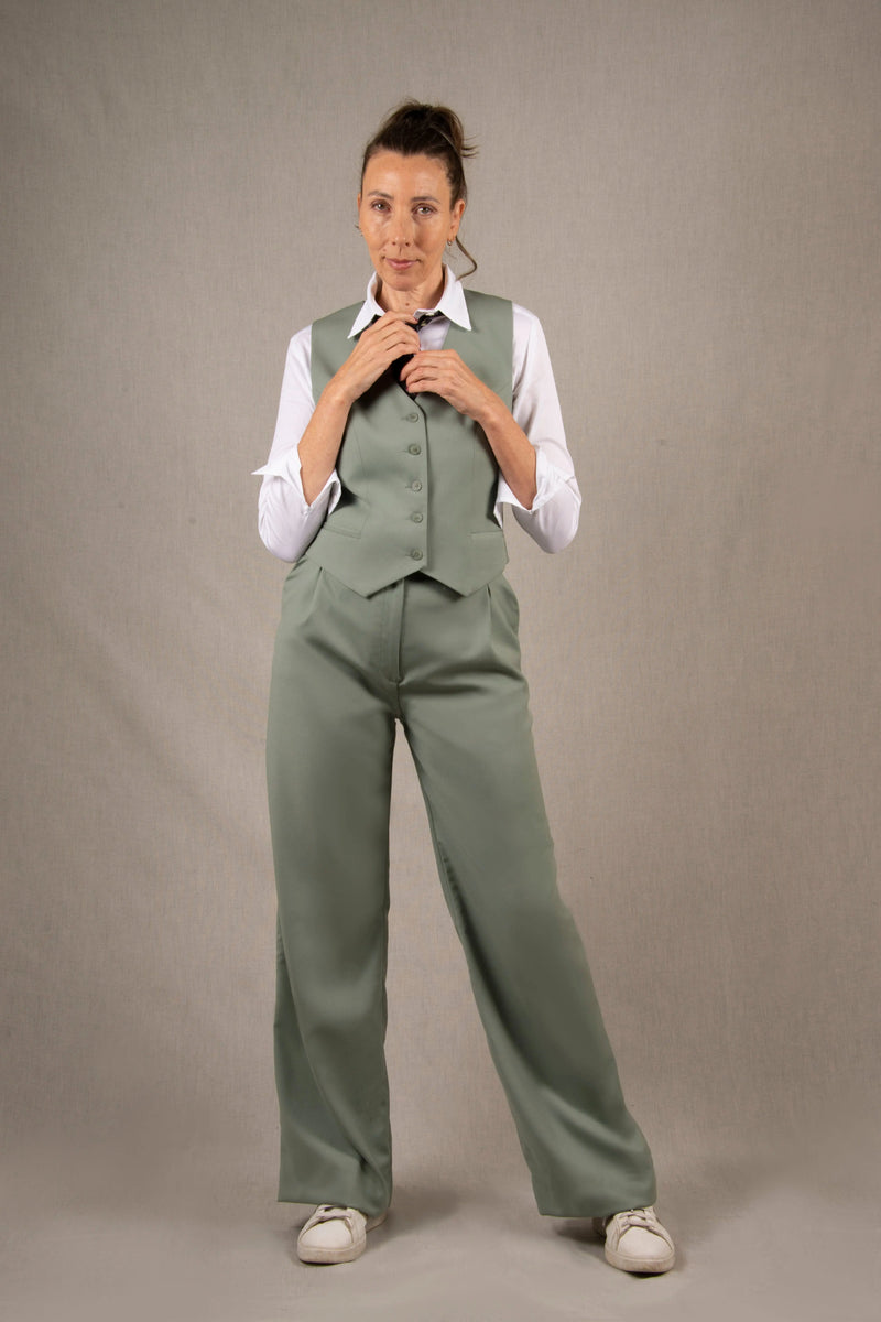 Pantalon tailleur laine, couleur vert sauge en 100% sergé laine. Deux poches latérales à l'italienne sur les côtés et ourlets invisibles sur le bas du pantalon. La coupe est fluide et large avec des plis pince devant, ainsi que des passants pour ceinture.