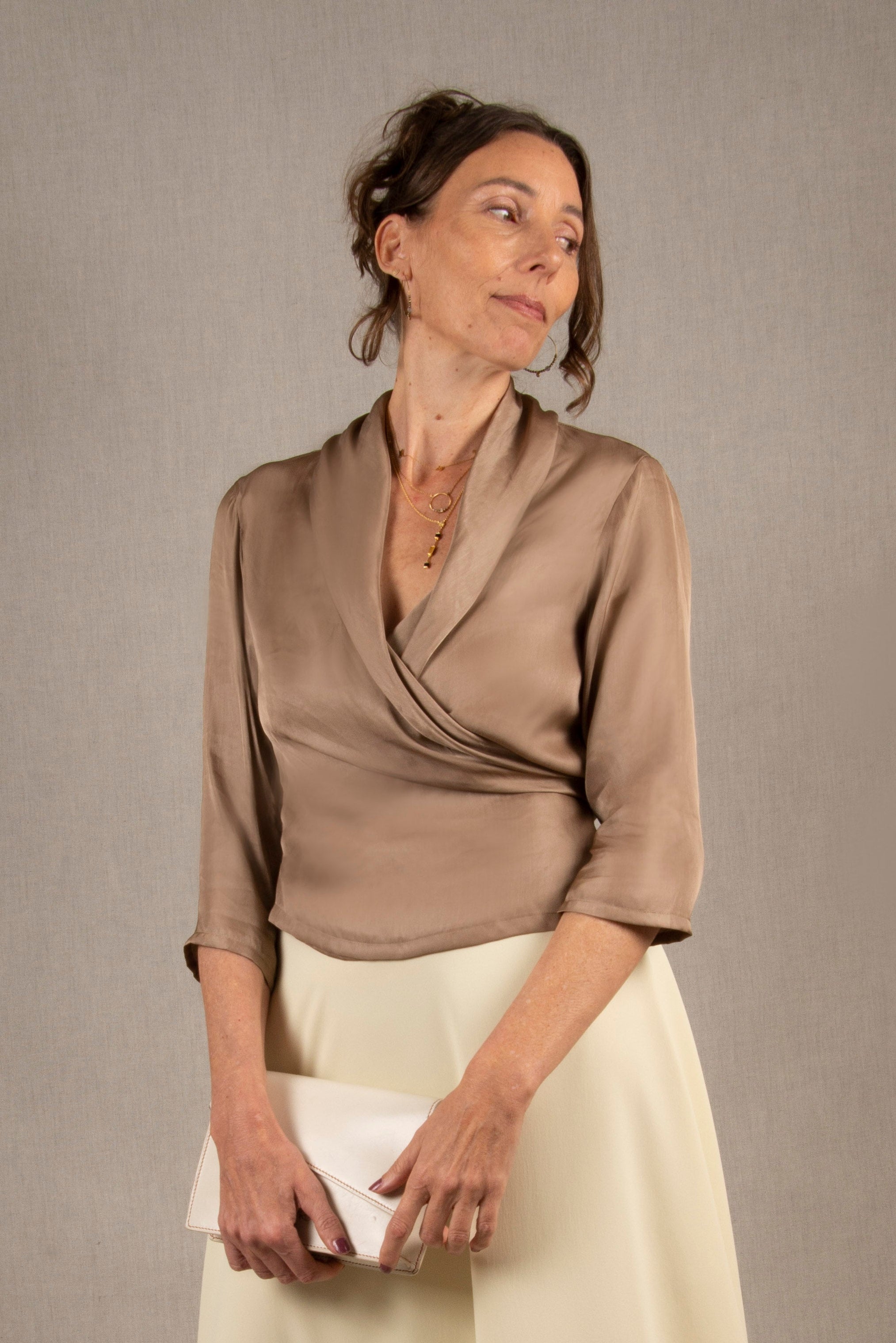 Ce cache-cœur a une coupe portefeuille croisée sur le devant avec des liens à nouer et maintenus par des passants latéraux. Le tissu est fluide, avec un décolleté drapé. La longueur arrive aux hanches. Les manches sont de 3/4 et droites et il y a des fronces sur l'encolure du dos.