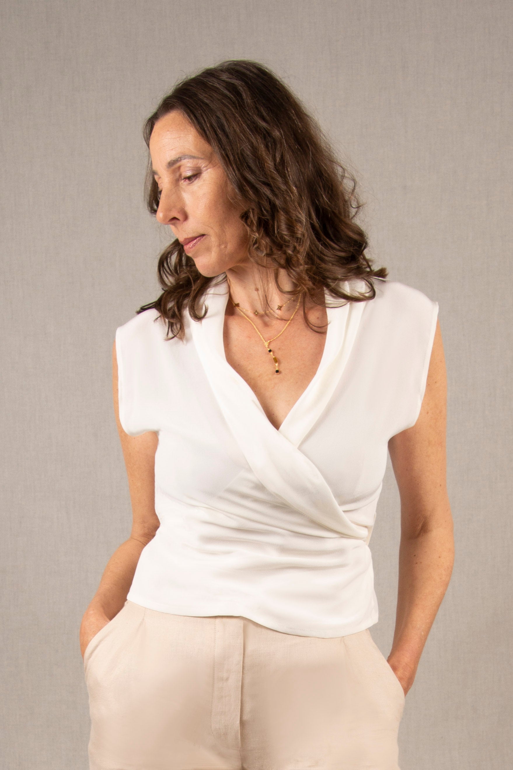 Ce cache-cœur sans manches a un col châle savamment plissé qui se croise sur le devant et épouse joliment la poitrine. Il se ferme à l’aide de deux liens à nouer dans le dos.