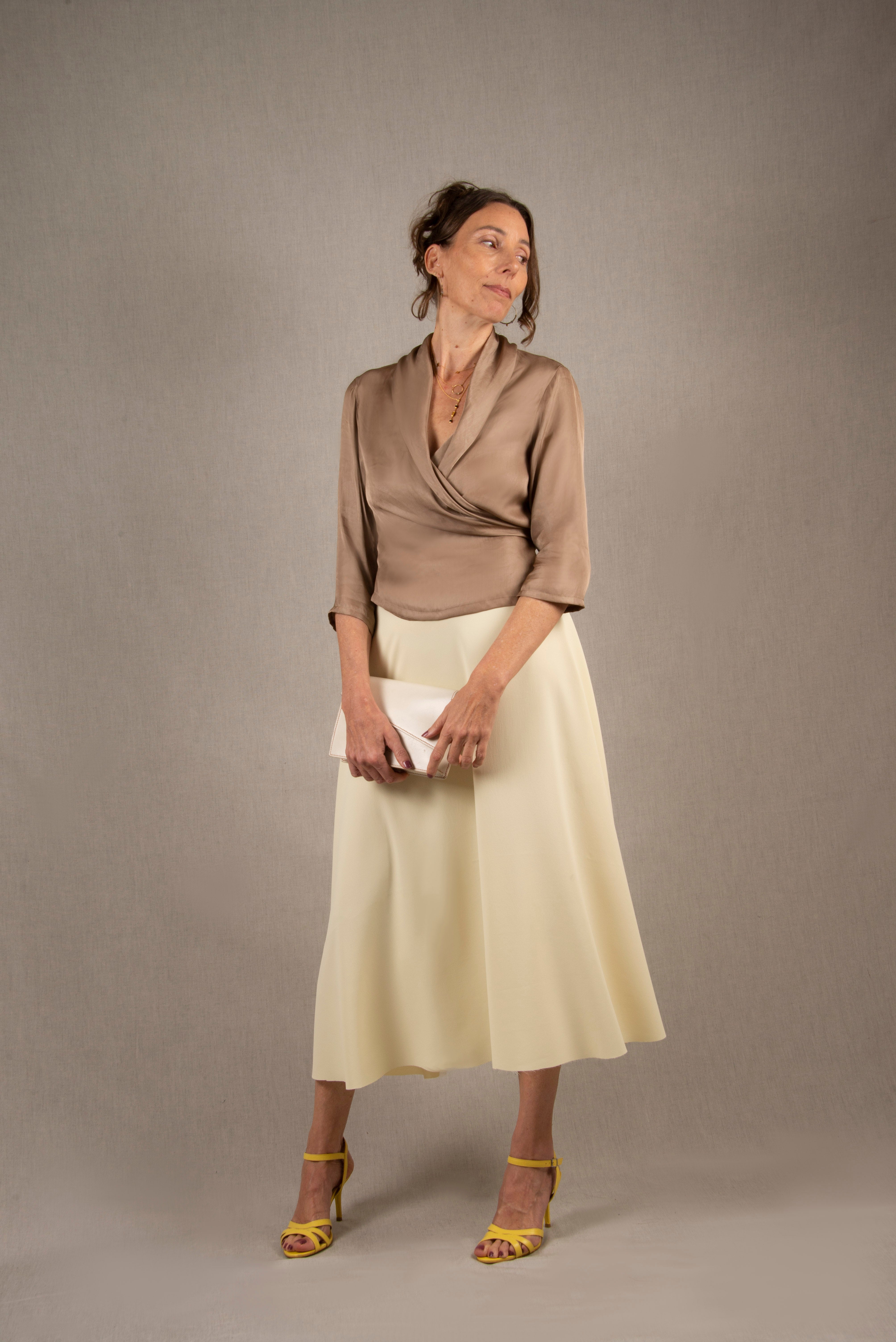 Cette jupe a une coupe longue et évasée, également pourvue d'une taille haute. Elle a un tombé fluide. Elle a une fermeture zippée invisible à l'arrière avec une agrafe métallique de maintien à la taille.