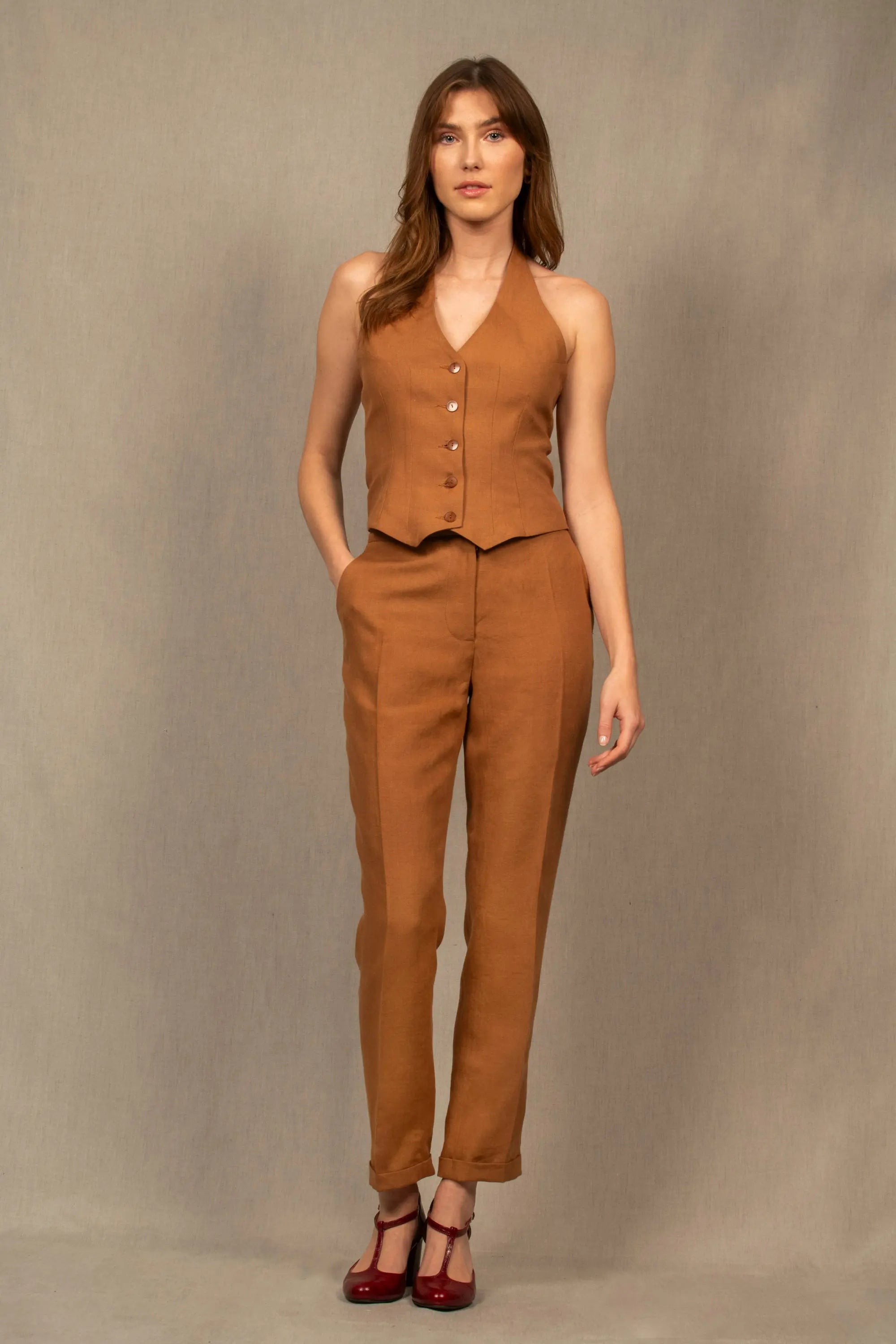 Pantalon femme tailleur 100% laine. Coupe légèrement fittée, pourvu de deux poches à l’Italienne sur le devant et une poche passepoilée fermée par un bouton à l’arrière.