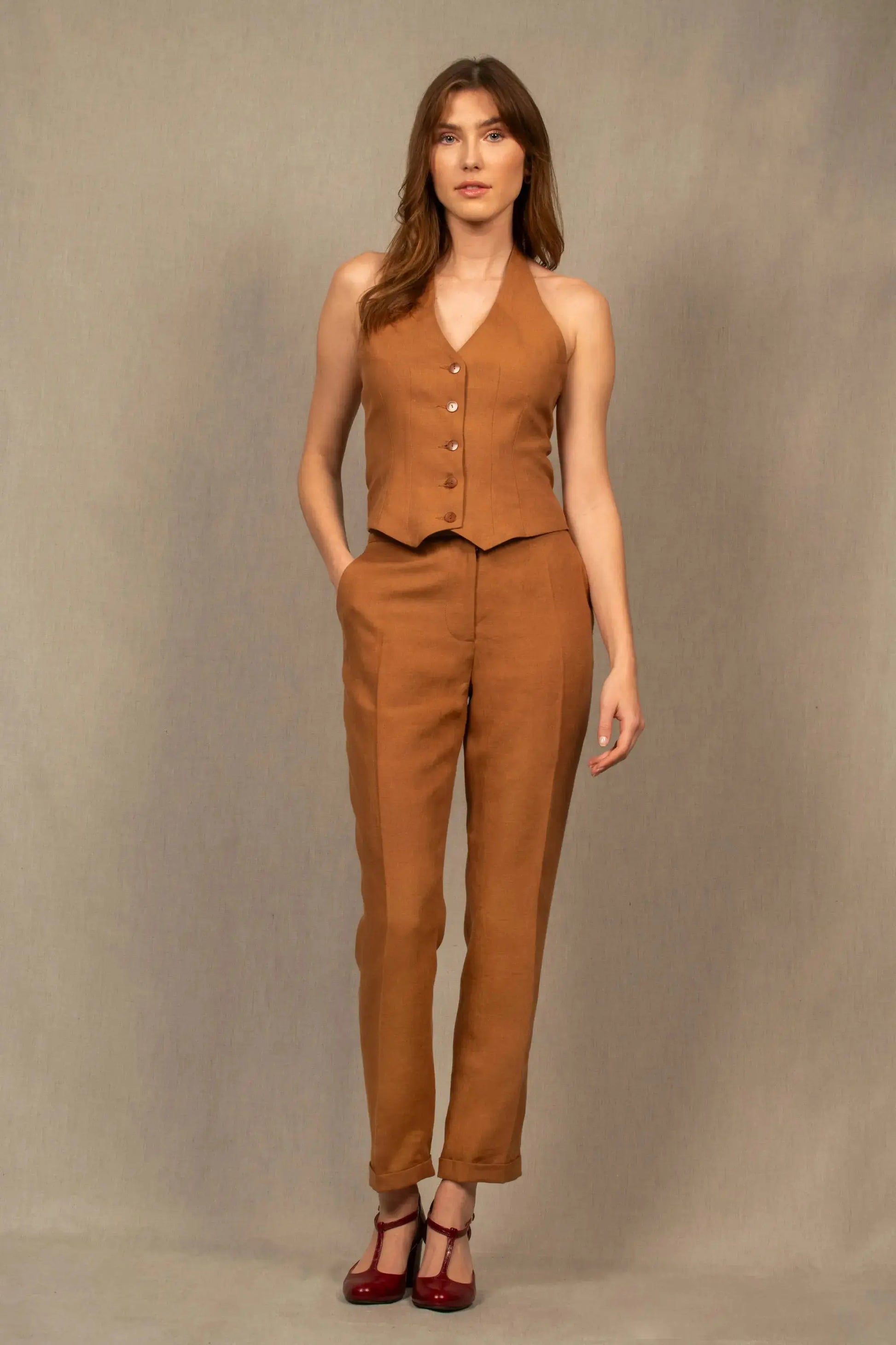 Pantalon femme tailleur 100% laine. Coupe légèrement fittée, pourvu de deux poches à l’Italienne sur le devant et une poche passepoilée fermée par un bouton à l’arrière.