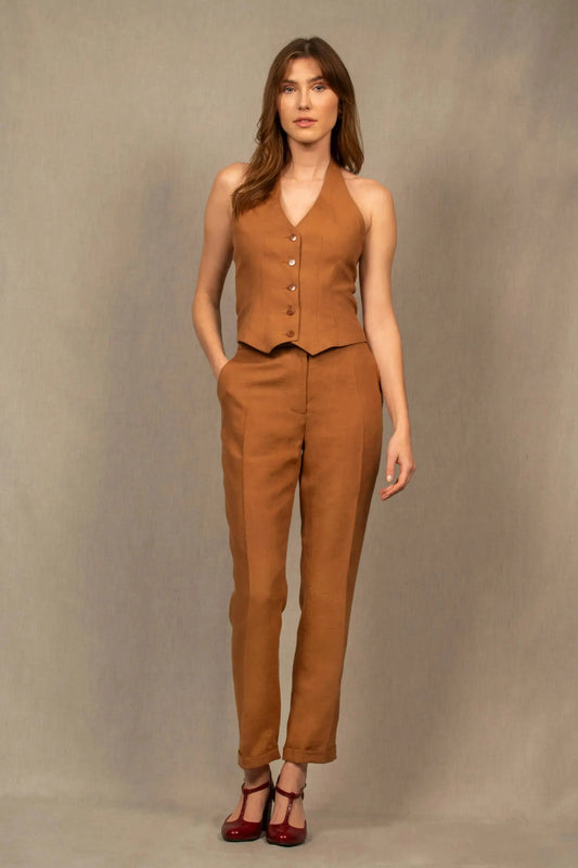 Pantalon femme tailleur 100% laine. Coupe légèrement fittée, pourvu de deux poches à l’Italienne sur le devant et une poche passepoilée fermée par un bouton à l’arrière.