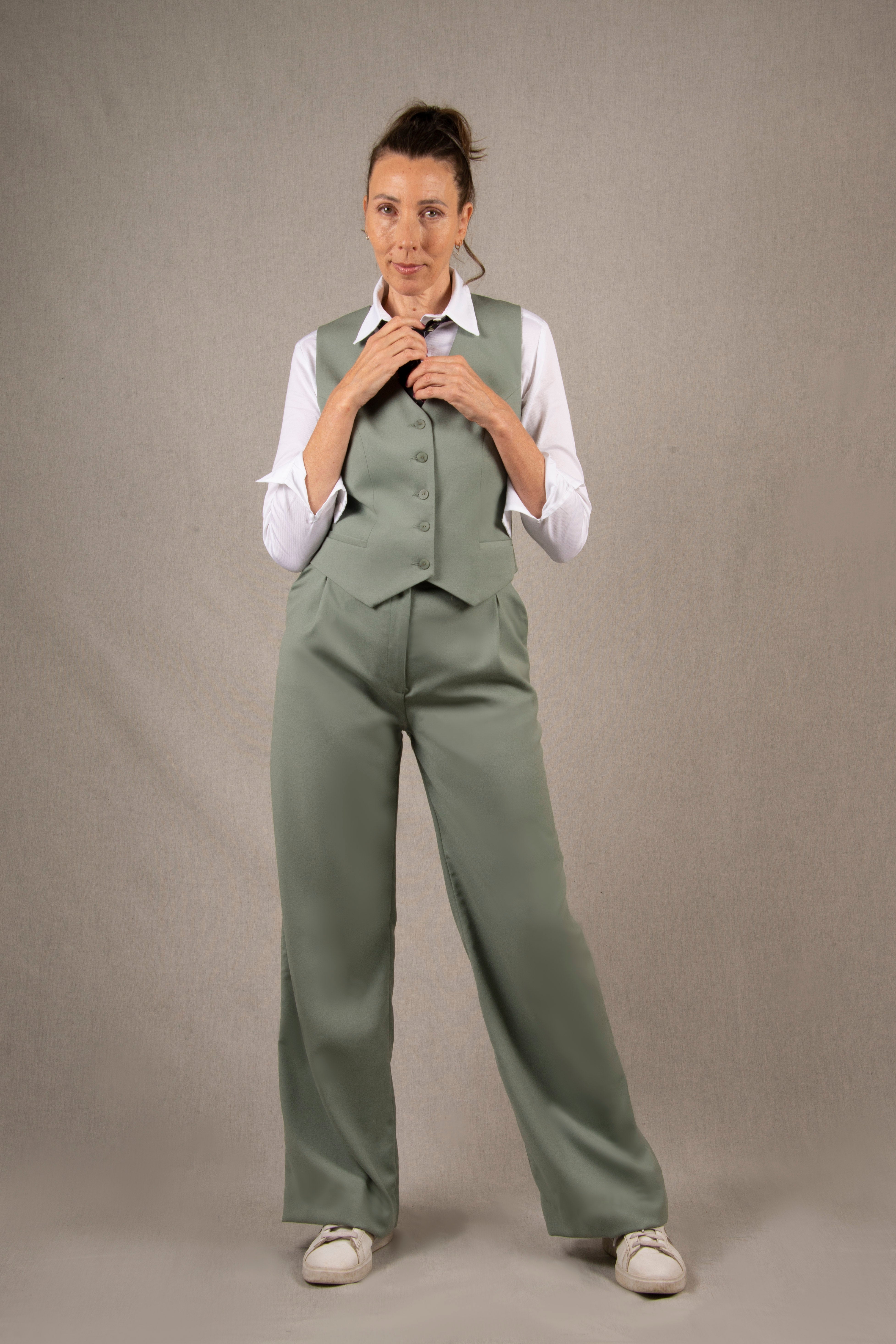 Pantalon tailleur laine, couleur vert sauge en 100% sergé laine. Deux poches latérales à l'italienne sur les côtés et ourlets invisibles sur le bas du pantalon. La coupe est fluide et large avec des plis pince devant, ainsi que des passants pour ceinture. 