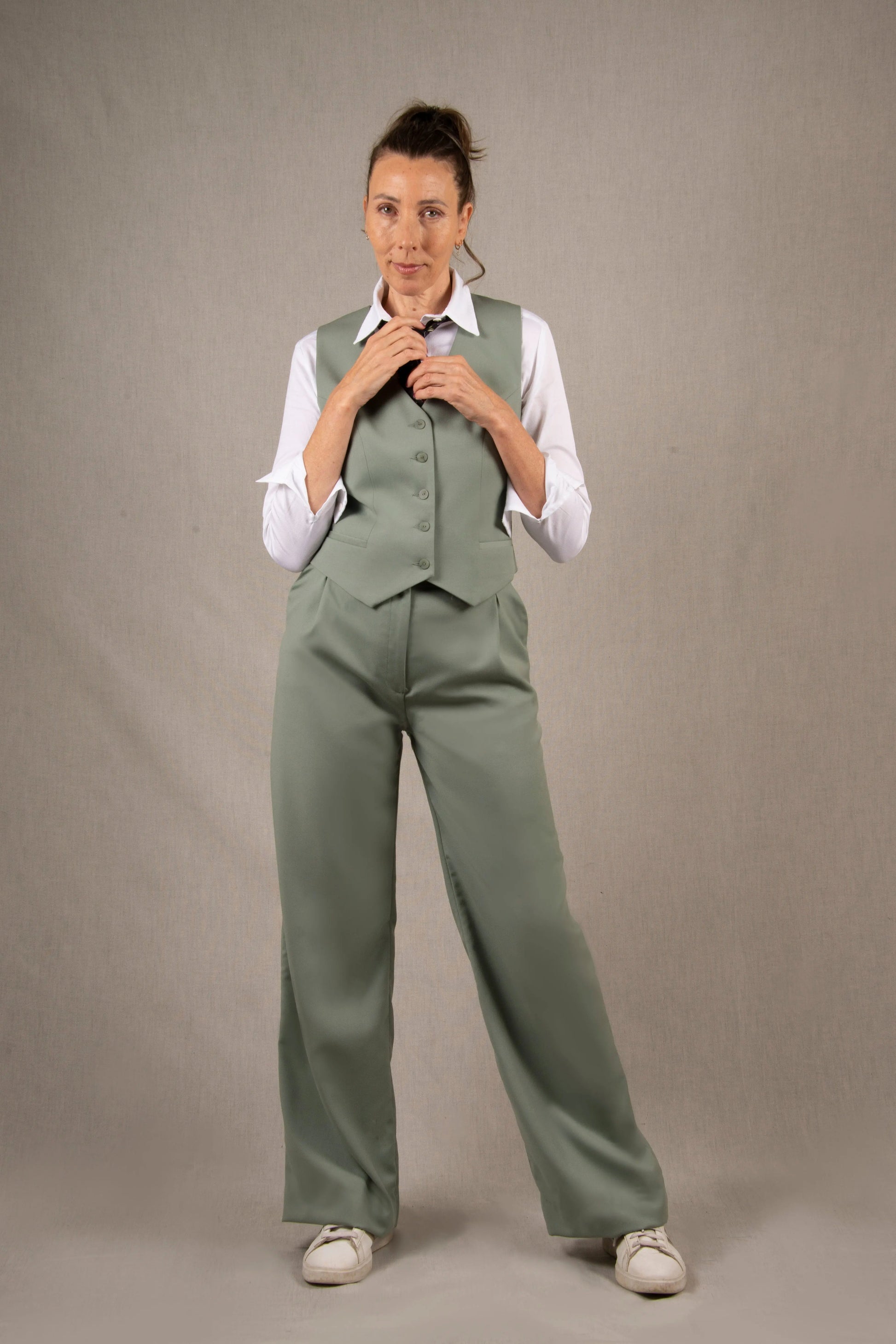 Pantalon tailleur laine, couleur vert sauge en 100% sergé laine. Deux poches latérales à l'italienne sur les côtés et ourlets invisibles sur le bas du pantalon. La coupe est fluide et large avec des plis pince devant, ainsi que des passants pour ceinture. 