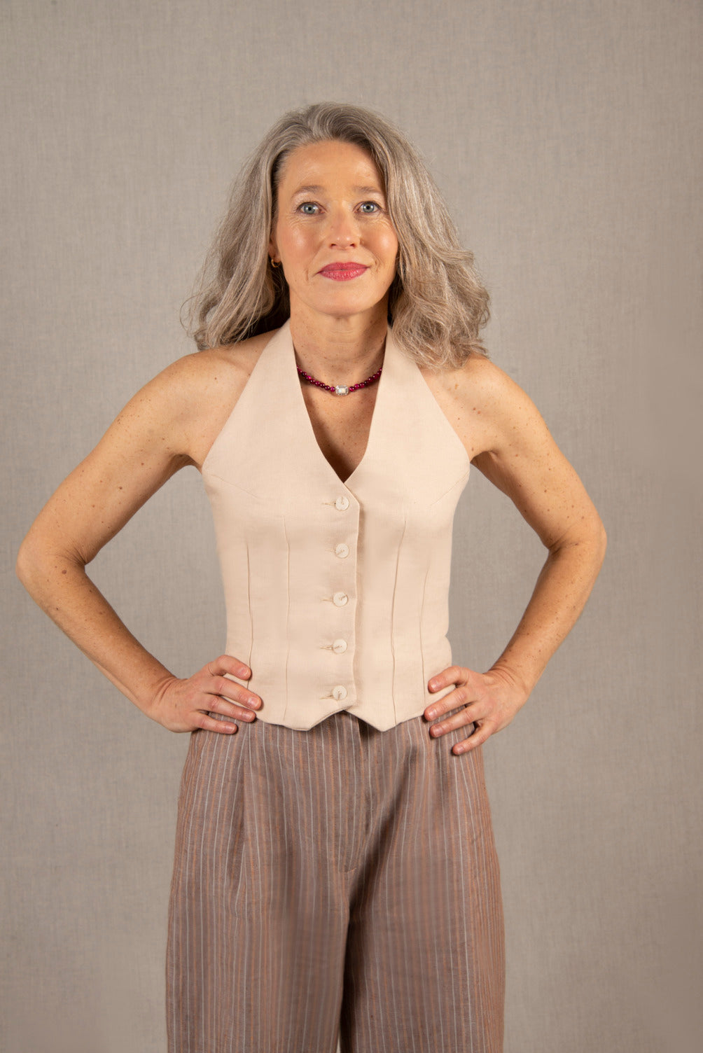 Ce gilet dos nu est en 100% lin, couleur ivoire. De nombreuses pinces cintrent le top et galbent le buste.
Il se ferme par une série de 5 boutons mates ton sur ton et sa hauteur se règle grâce à un jeu de coulisse dans le cou.