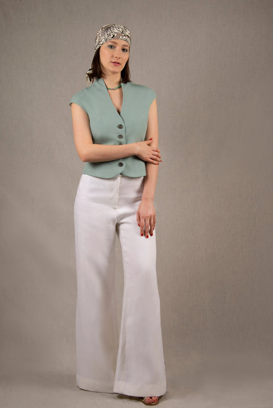 Le pantalon est 100% lin et est monté sur une large ceinture croisée et terminée par des boutons irisés. Il s’évase largement vers le bas. Sur le devant, deux poches en biais à faux passepoils.