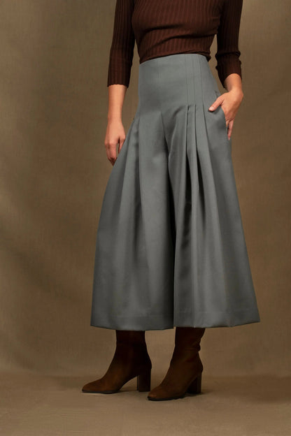 Ce pantalon femme se distingue par une élégante silhouette évasée. Pantalon taille haute ponctué par de larges plis sur le devant, ce modèle cintré à la taille flatte votre silhouette. Il comporte deux poches dans la couture, sur chaque côtés. Une fermeture éclair invisible se situe à l’arrière. Longueur au dessus de la cheville.