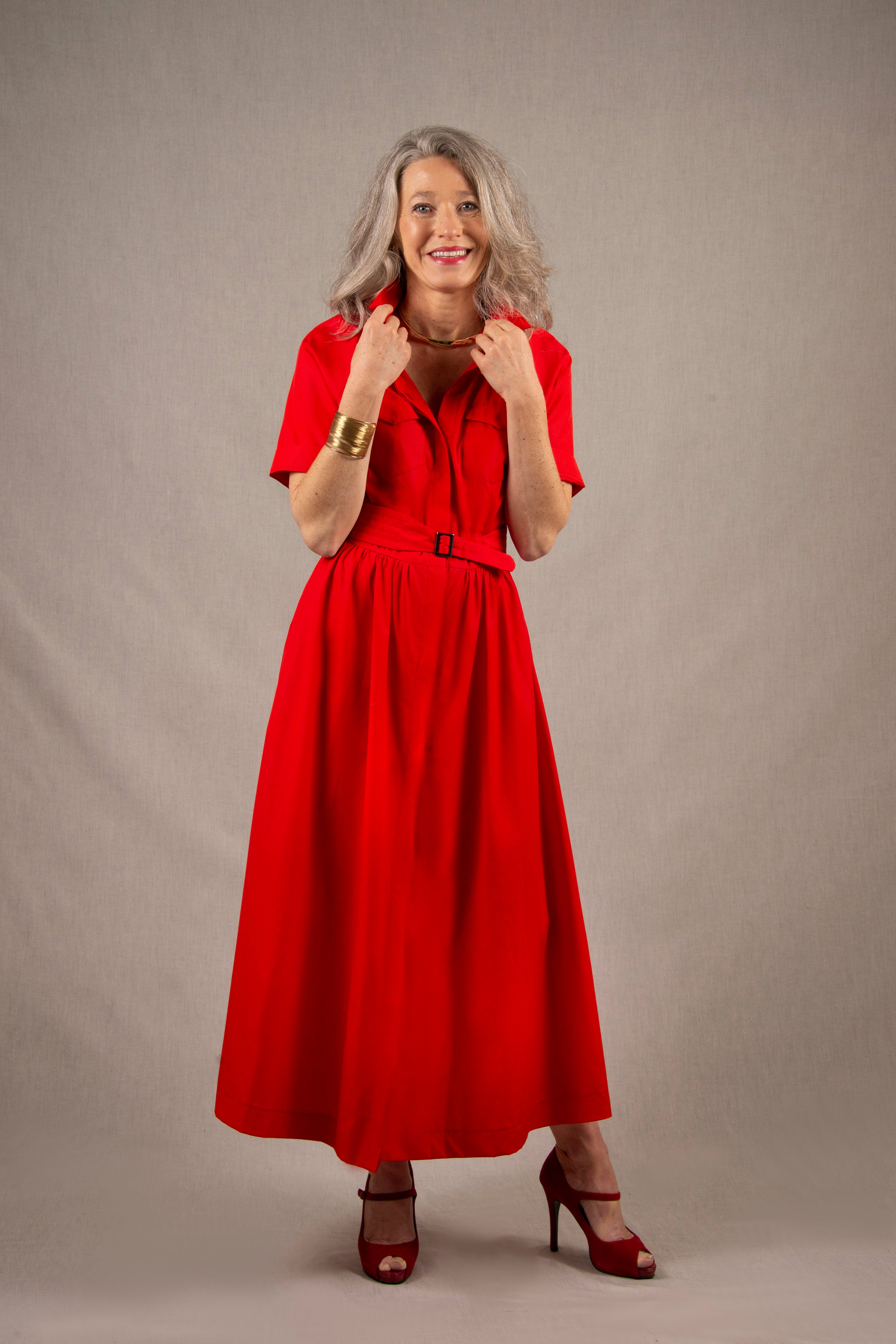 Cette robe chemisier 100% coton, à longueur sous-mollet, a un boutonnage caché sur tout le milieu devant. Elle a des manches courtes raglan avec une série de plis à la base, ainsi que deux poches plaquées à rabat sur la poitrine et deux poches sur les côtés dans la couture. Il y a un smock au milieu du dos pour cintrer la taille et une ceinture large surpiquée finie par une boucle en métal.