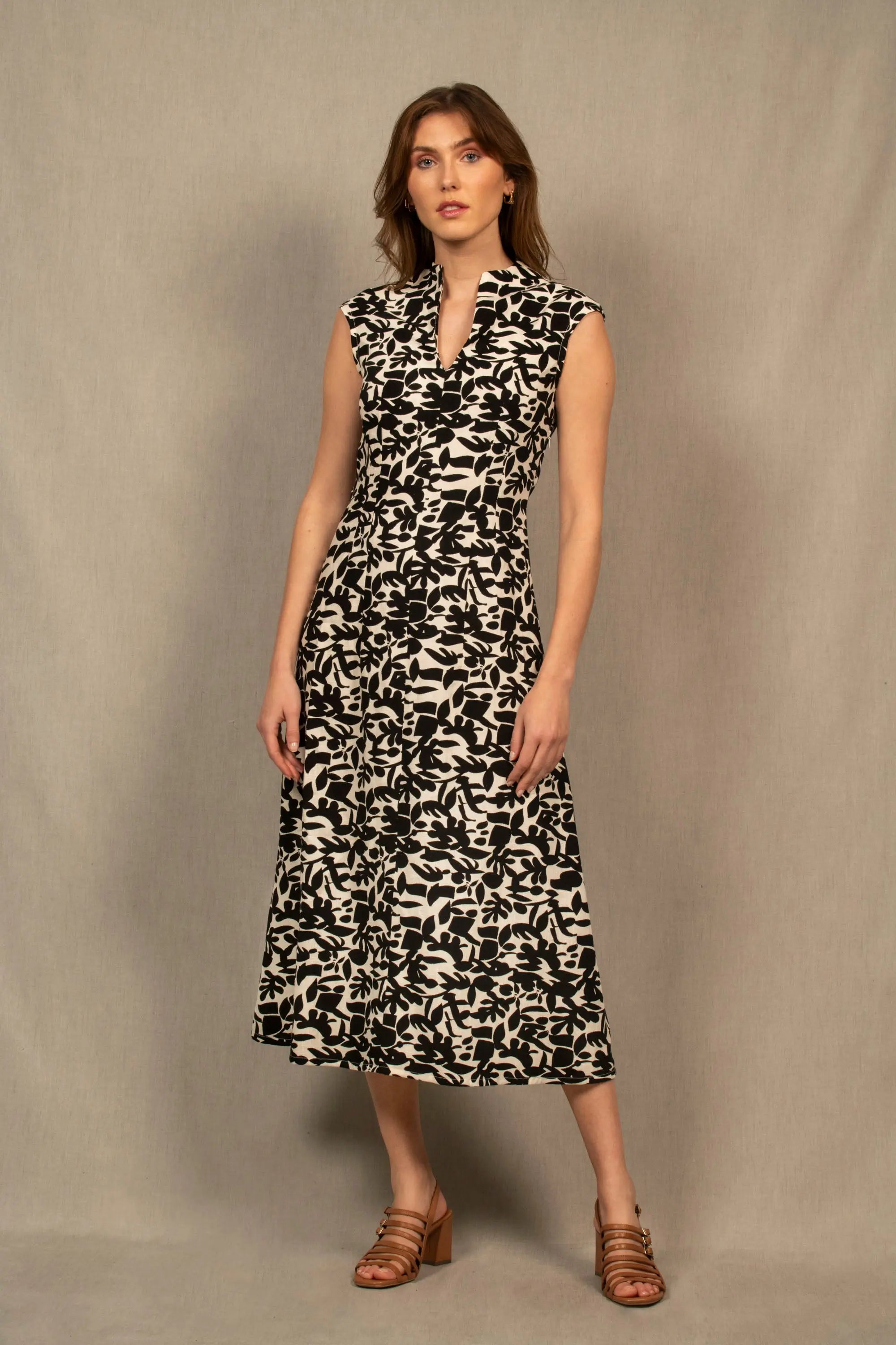 Robe légèrement évasée longueur à la cheville. La taille est marquée par un jeu de pinces. Il y a un ouverture dans le bas du dos au niveau de la taille. Fermeture par zip invisible côté gauche. Col légèrement montant avec fente milieu devant.