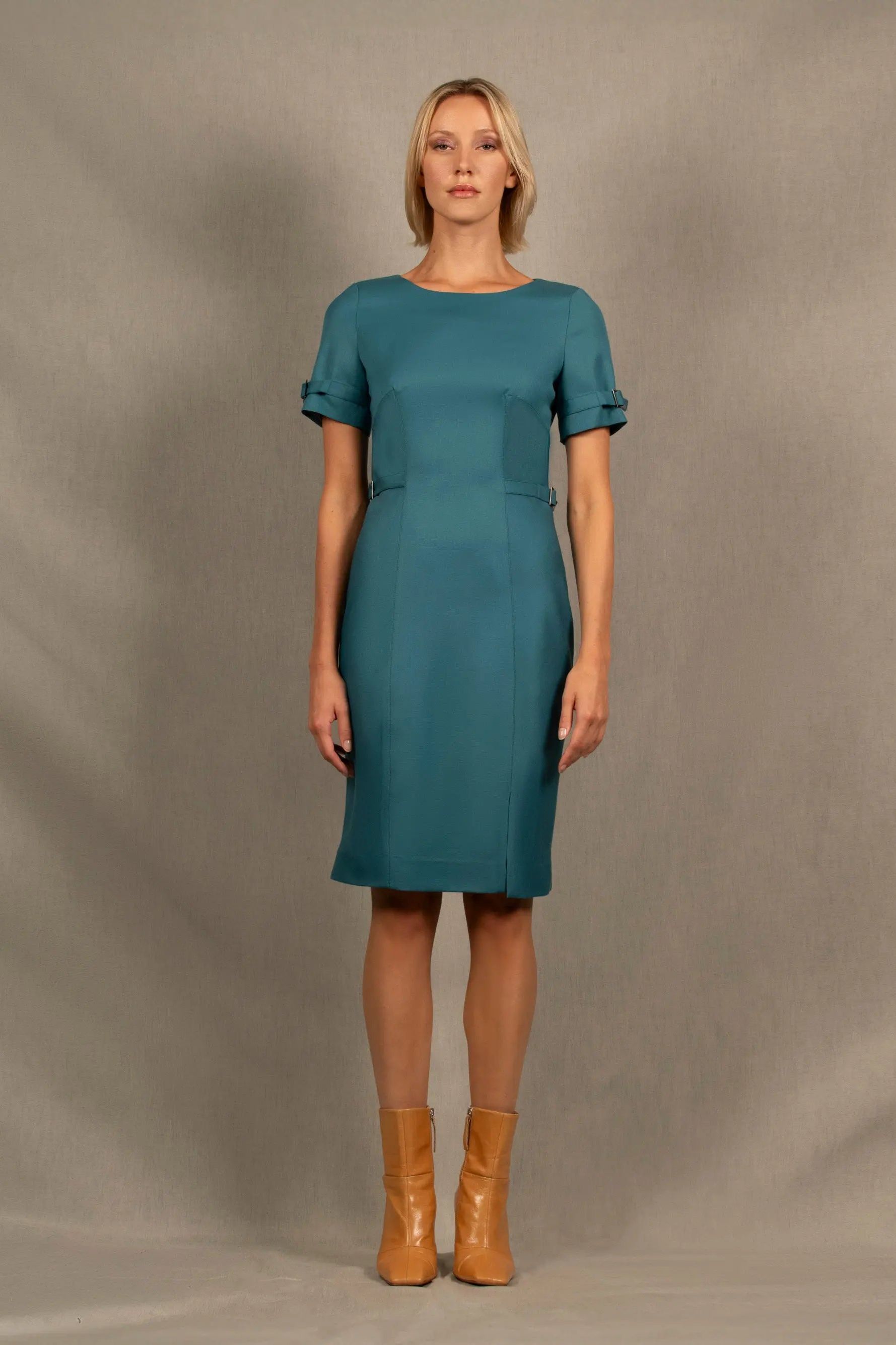 Cette robe en laine couleur bleu pacifique a une coupe cintrée mi-longue avec encolure ronde, découpes structurantes devant et dos, petite fente sur le côté gauche et fermeture zippée au milieu du dos.