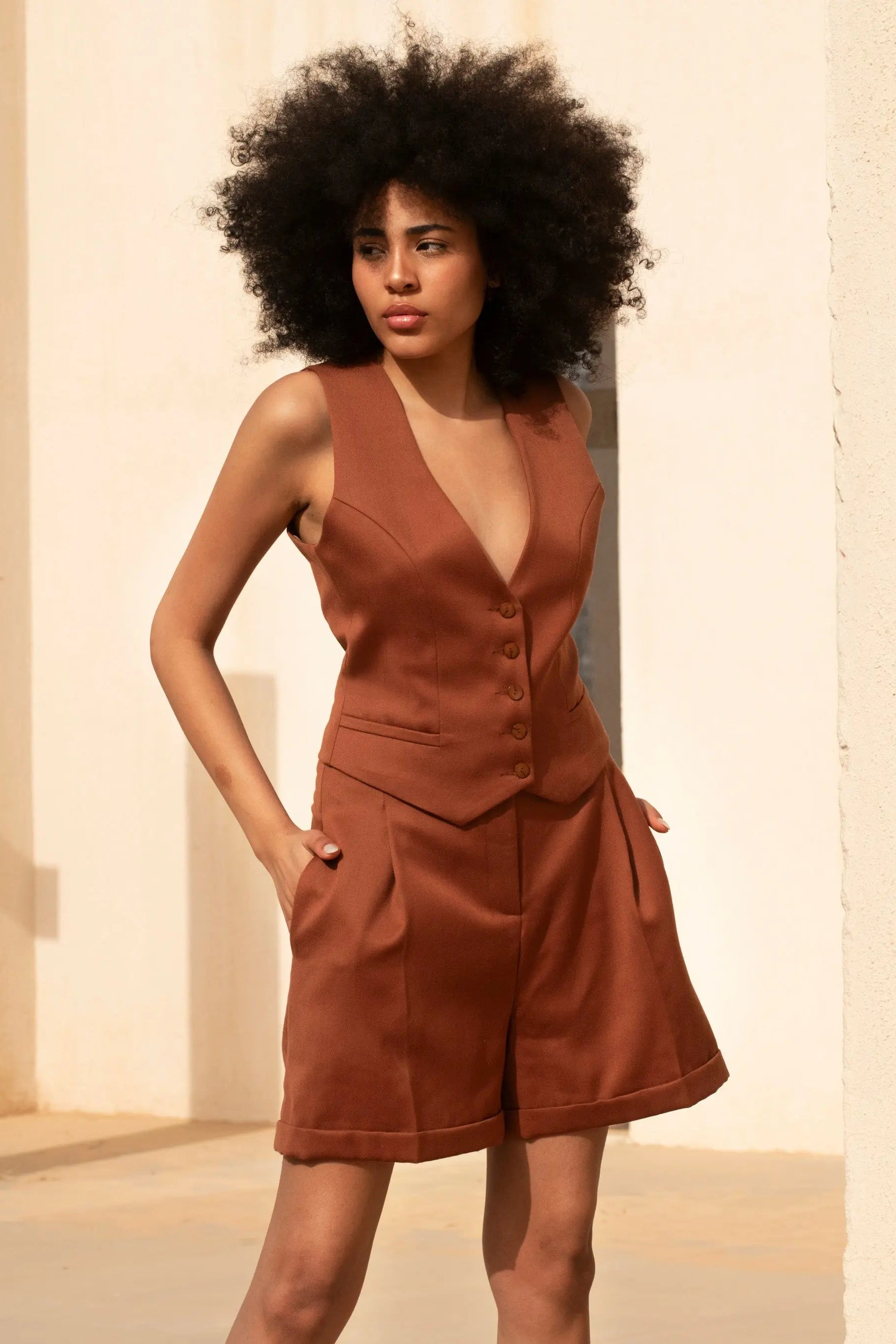 Short tailleur femme couleur terra cotta en 100% laine, taille haute, plis marqués sur le devant, deux poches latérales, longueur mi-cuisse. Coupe évasée sur le bas.