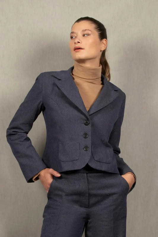 En bleu jean, cette veste femme courte marque la taille. Elle présente des découpes princesses sur le dos et le devant. Elle a deux fentes dans le dos pour accentuer la cambrure. Fermée par une série de 3 boutons irisés reportés également sur le bas des manches, ainsi que deux petites poches plaquées agrémentent le devant.