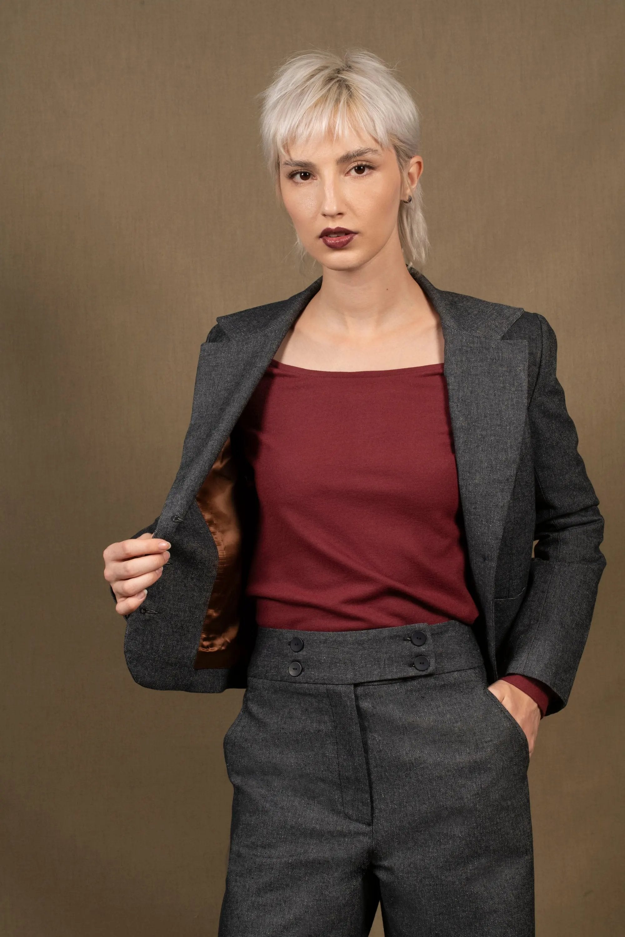 Cette veste femme courte marque la taille. Elle présente des découpes princesses sur le dos et le devant. Elle a deux fentes dans le dos pour accentuer la cambrure. Fermée par une série de 3 boutons irisés reportés également sur le bas des manches, ainsi que deux petites poches plaquées agrémentent le devant.