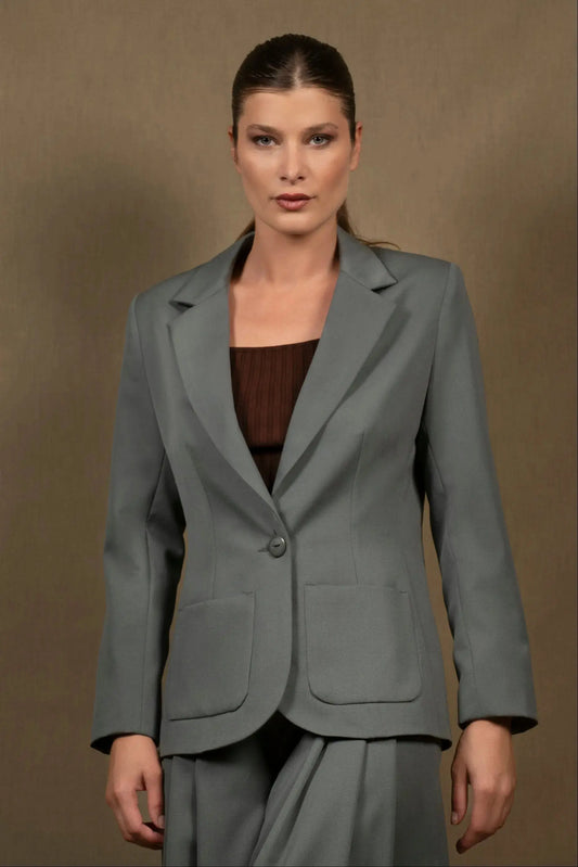 Veste tailleur femme qui est soulignée par deux poches sur chaque côté. Coupe structurée et cintrée. Elle présente un col tailleur. Boutonnage simple.