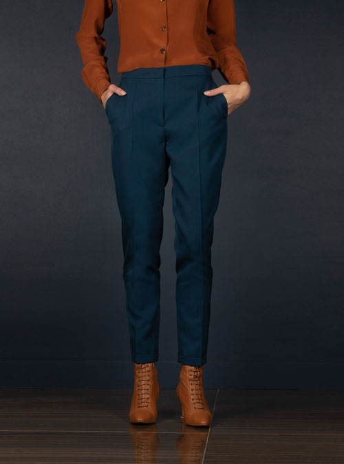 Coupe légèrement fittée pour ce pantalon tailleur femme en laine bleu pétrole, pourvu de deux poches à l’Italienne sur le devant et une poche passepoilée fermée par un bouton à l’arrière.