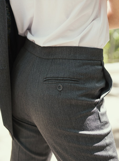 Coupe légèrement fittée, ce pantalon est pourvu de deux poches à l’italienne sur le devant et une poche passepoilée fermée par un bouton à l’arrière. Il est monté sur une ceinture étroite et est doublé jusqu’au genou. Un revers vient terminer l’ourlet.